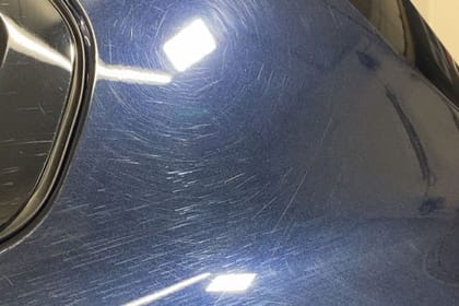 Dunkelblaue Heckpartie vor der Politur: feine Kratzer im Lack, im Licht der Werkstattlampen deutlich sichtbar.