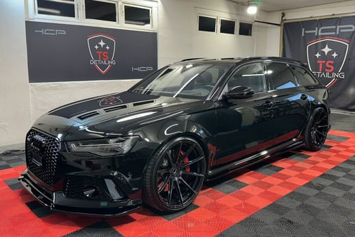 Schwarzer Audi RS6 Avant im Studio von TS Detailing, dahinter zwei Banner an der Wand.