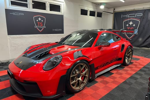 Roter Porsche 911 GT3 RS im Studio von TS Detailing, dahinter zwei Banner an der Wand.