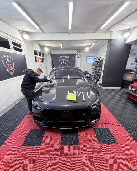 Tefik Sacipi poliert einen schwarzen Sportwagen in seinem Studio in Winterthur.
